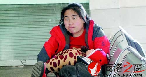 候車廳里，一位母親抱著睡著的孩子發呆